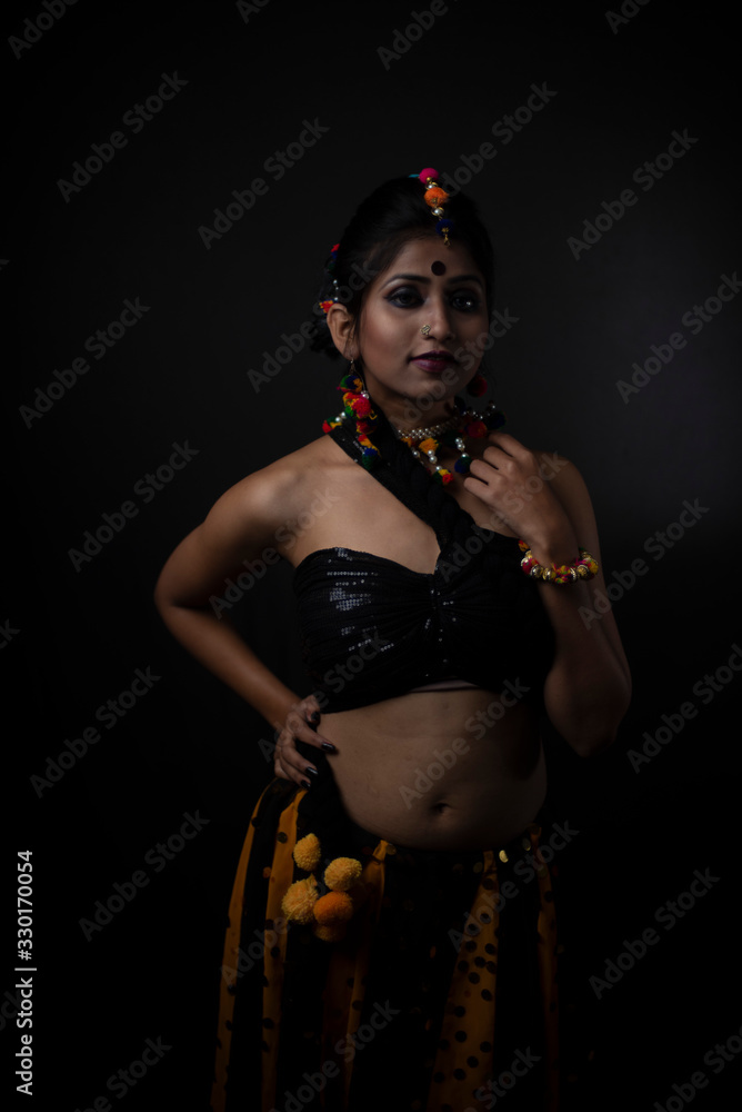 Fashion portrait of Indian brunette woman in Indian traditional tribal dress and handmade ornaments in dark copy space studio background.Indian lifestyle and fashion photography. Fashion portrait of Indian brunette woman in Indian traditional tribal dress and handmade ornaments in dark copy space studio background.Indian lifestyle and fashion photography.