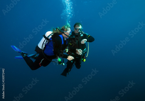 Happy couple scuba divers hovering together on a safety stop.