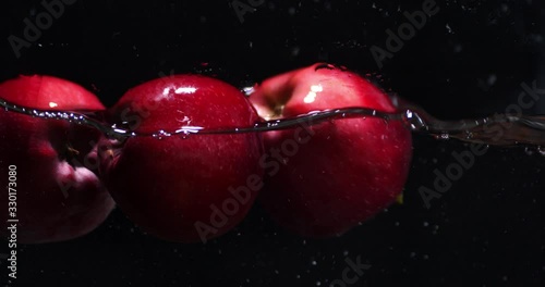 Red fresh apples fall into the water.