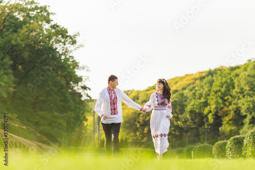 guy and a girl in embroidered clothes hold hands and run. couple