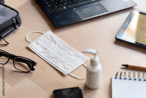 remote work kit on wooden office desk with hand sanitizer and face mask, a solution against the spread of corona virus for quarantined employees photo