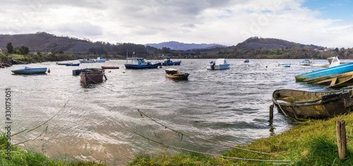 Panoramic view of small fishing boats moored with mountains and