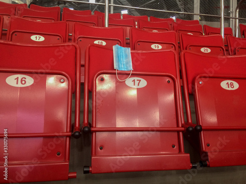 The concept of coronavirus affects sports. An empty stadium stands because of a coronavirus. Protective mask on empty stadium chairs. Cancellation of competition due to pandemic. Sport is stopped photo