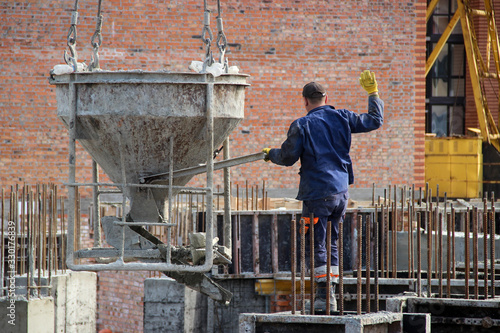 Workers at construction site casting a concrete mixture into the form, creating demountable and permanent formwork photo