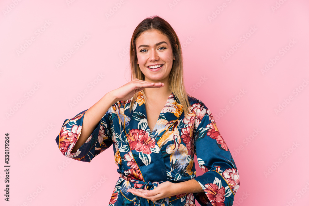 Young caucasian woman wearing pajamas holding something with both hands, product presentation. Young caucasian woman wearing pajamas holding something with both hands, product presentation.
