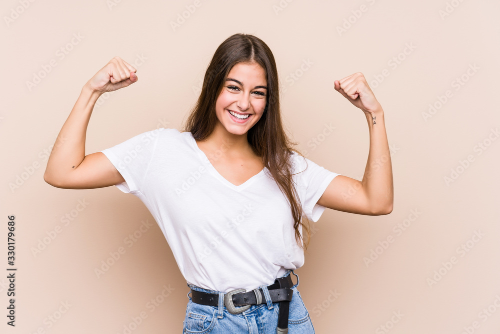 Young caucasian woman posing isolated showing strength gesture with arms, symbol of feminine power Young caucasian woman posing isolated showing strength gesture with arms, symbol of feminine power
