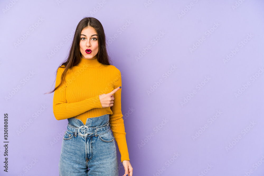 Young caucasian woman isolated on purple background pointing to the side Young caucasian woman isolated on purple background pointing to the side