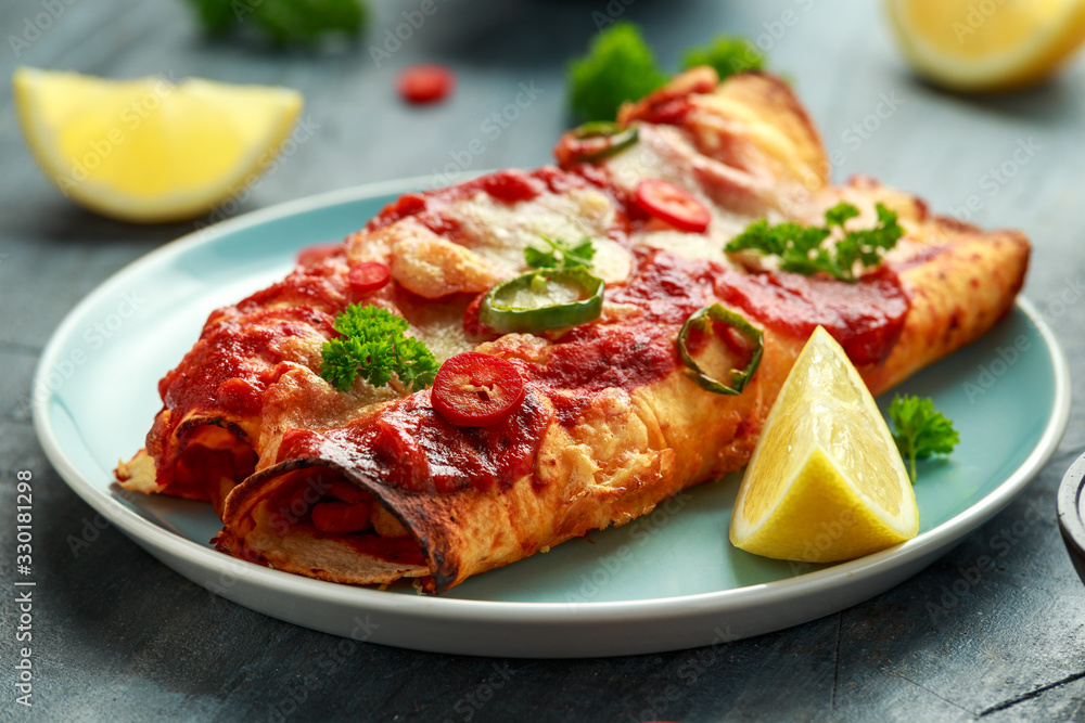 Baked Chicken fillets enchiladas with courgette, salsa sauce and cheese served with lemon wedges and chilies Baked Chicken fillets enchiladas with courgette, salsa sauce and cheese served with lemon wedges and chilies