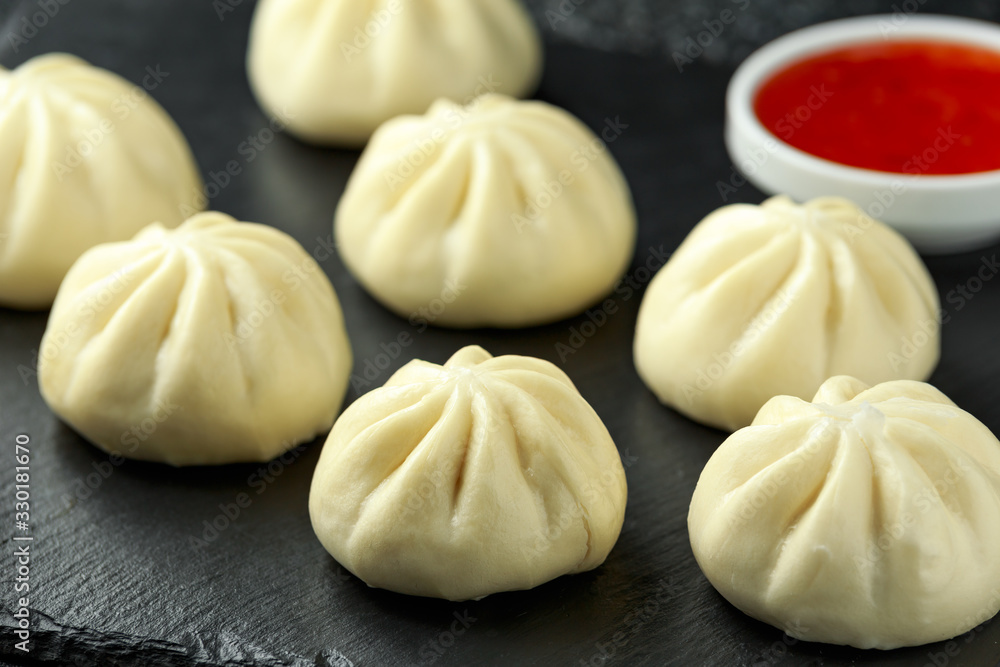 Steamed Buns with duck stuffing, chili sauce on rustic stone board. Asian food