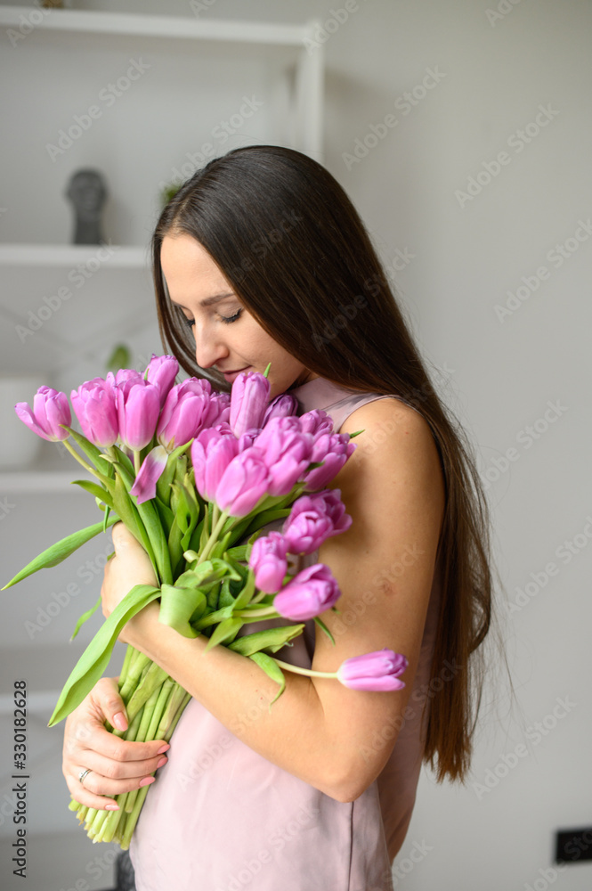 Spring mood. Beautiful woman with tulips indoors