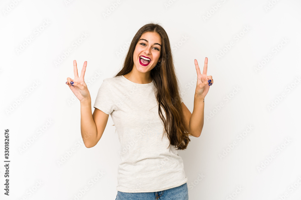 Young caucasian woman isolated on white background showing victory sign and smiling broadly. Young caucasian woman isolated on white background showing victory sign and smiling broadly.