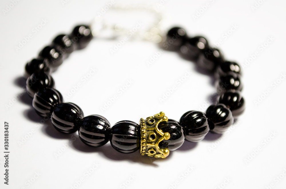 Bracelet made of black plastic beads with a crown-shaped decor. Unisex bracelet on a white background. Bead jewelry. Bijouterie. Macro photo. Bracelet made of black plastic beads with a crown-shaped decor. Unisex bracelet on a white background. Bead jewelry. Bijouterie. Macro photo.