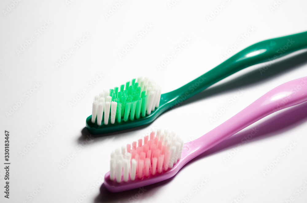 Two toothbrushes green and pink. A pair of personal care products on a white background. Dentistry and dentists. Teeth cleaning. Two toothbrushes green and pink. A pair of personal care products on a white background. Dentistry and dentists. Teeth cleaning.