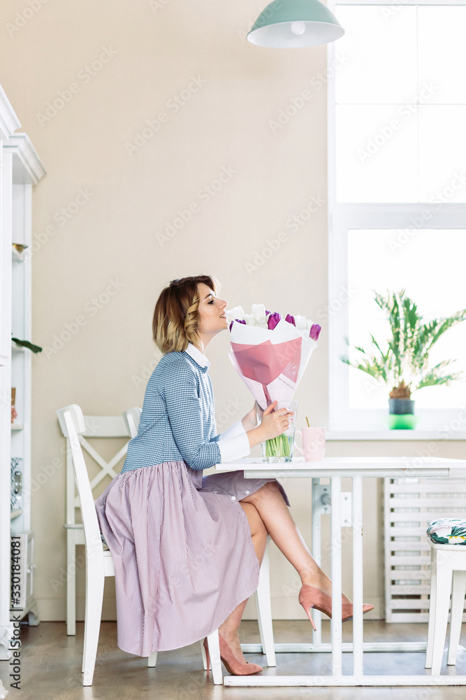 Beautiful young blond woman with tulip bouquet sitting at the table Beautiful young blond woman with tulip bouquet sitting at the table