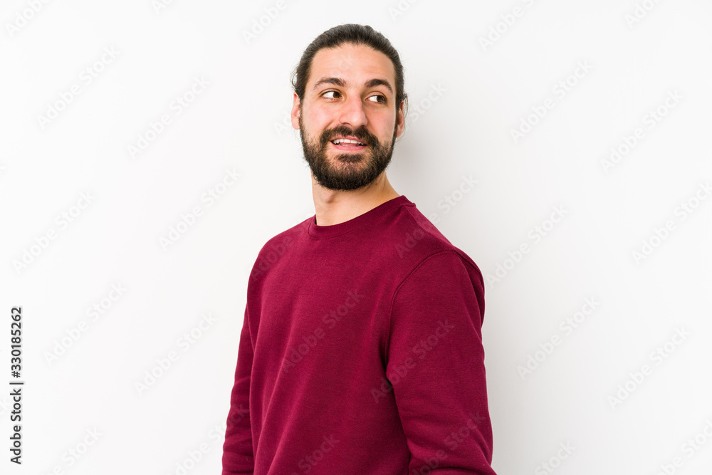 Fototapeta premium Young long hair man isolated on a white background looks aside smiling, cheerful and pleasant.