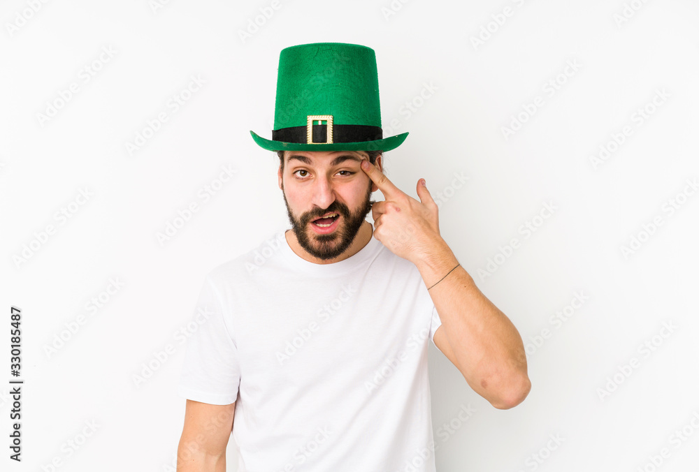 Young caucasian man wearing a saint patricks hat isolated showing a disappointment gesture with forefinger.