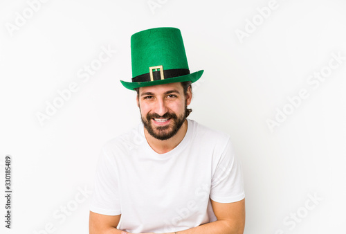 Young caucasian man wearing a saint patricks hat isolated laughing and having fun.