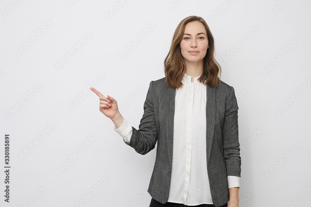 Beautiful businesswoman is looking happy and pointing at your product Beautiful businesswoman is looking happy and pointing at your product
