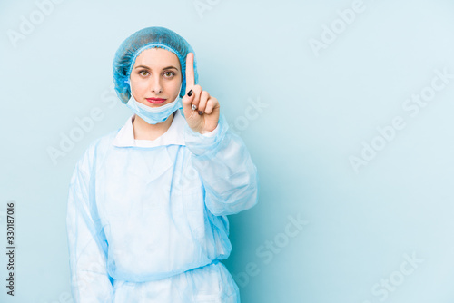 Young surgeon woman isolated showing number one with finger. © Asier