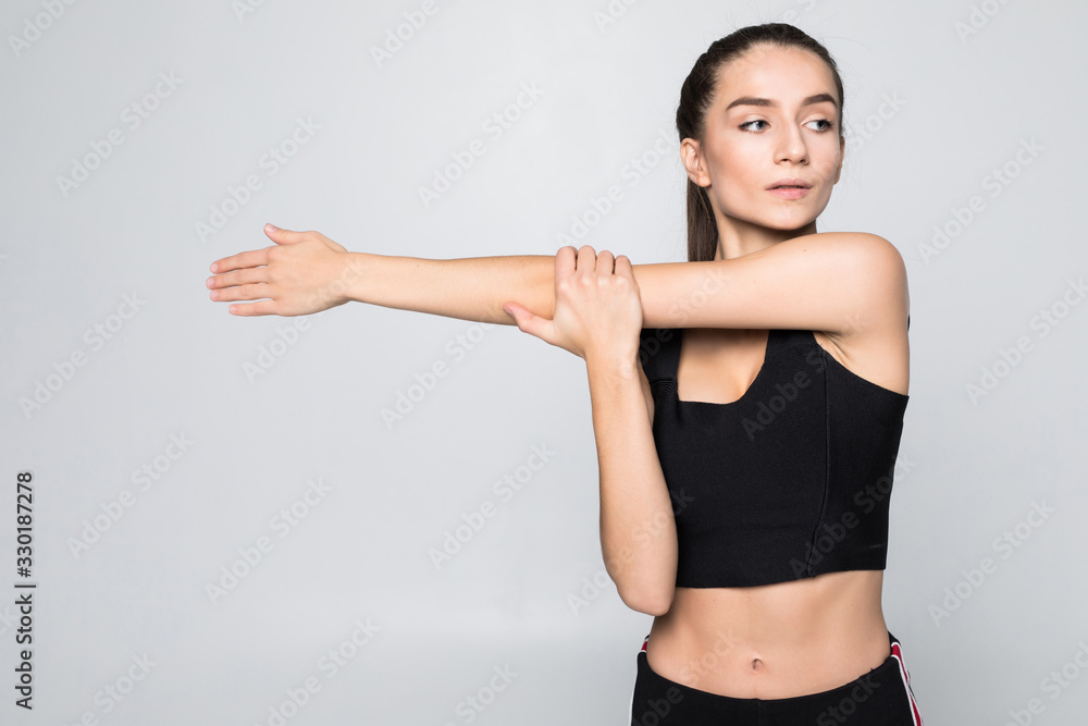 Portrait of a smiling fitness woman stretching her hands over white background