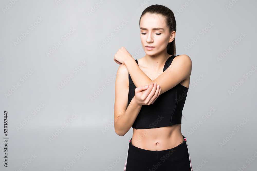 Upset brunette young woman injured arm during sport training, touches her wrist isolated on white background Upset brunette young woman injured arm during sport training, touches her wrist isolated on white background