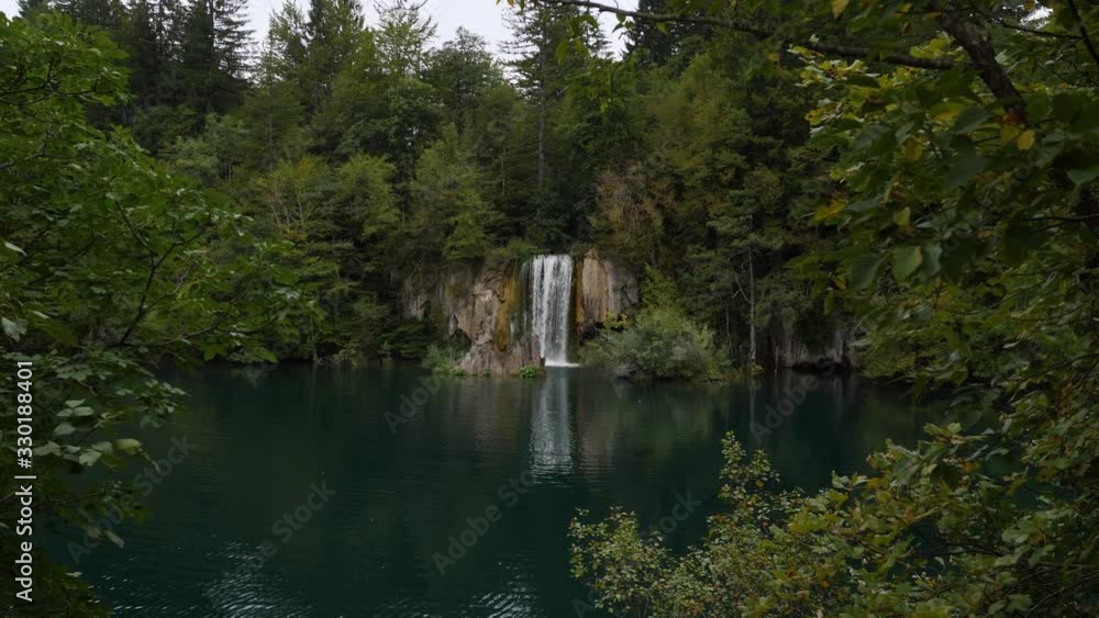 Waterfall falls into Plitvice Lake. Scenery landscape of cloudy forest around water. Croatia Waterfall falls into Plitvice Lake. Scenery landscape of cloudy forest around water. Croatia