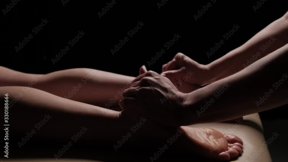Massage of female legs, feet closeup on a black background. Slow motion. Thai massage. Massage of female legs, feet closeup on a black background. Slow motion. Thai massage.