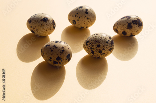 Five quail eggs with shadows on the yellow background. Minimalistic conceptual composition for Easter Holiday.