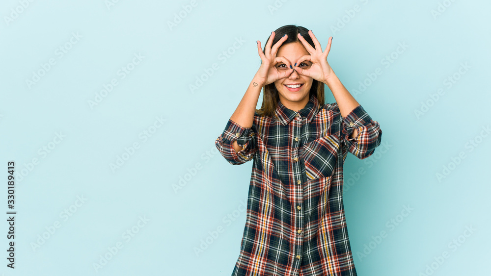 Young woman isolated on blue background excited keeping ok gesture on eye. Young woman isolated on blue background excited keeping ok gesture on eye.
