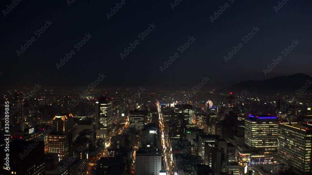 SAPPORO, HOKKAIDO, JAPAN - FEB 2020 : Aerial high angle sunrise view of cityscape of Sapporo city. View of buildings and street traffic around Susukino downtown area. Time lapse shot night to morning. SAPPORO, HOKKAIDO, JAPAN - FEB 2020 : Aerial high angle sunrise view of cityscape of Sapporo city. View of buildings and street traffic around Susukino downtown area. Time lapse shot night to morning.