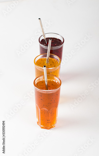 Herbal fruit berry drink in a glass, pineapple with Basil, pomegranate with mint, sea buckthorn with oregano on a white background