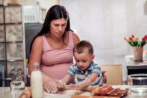 Pregnant woman and son making cookies.
