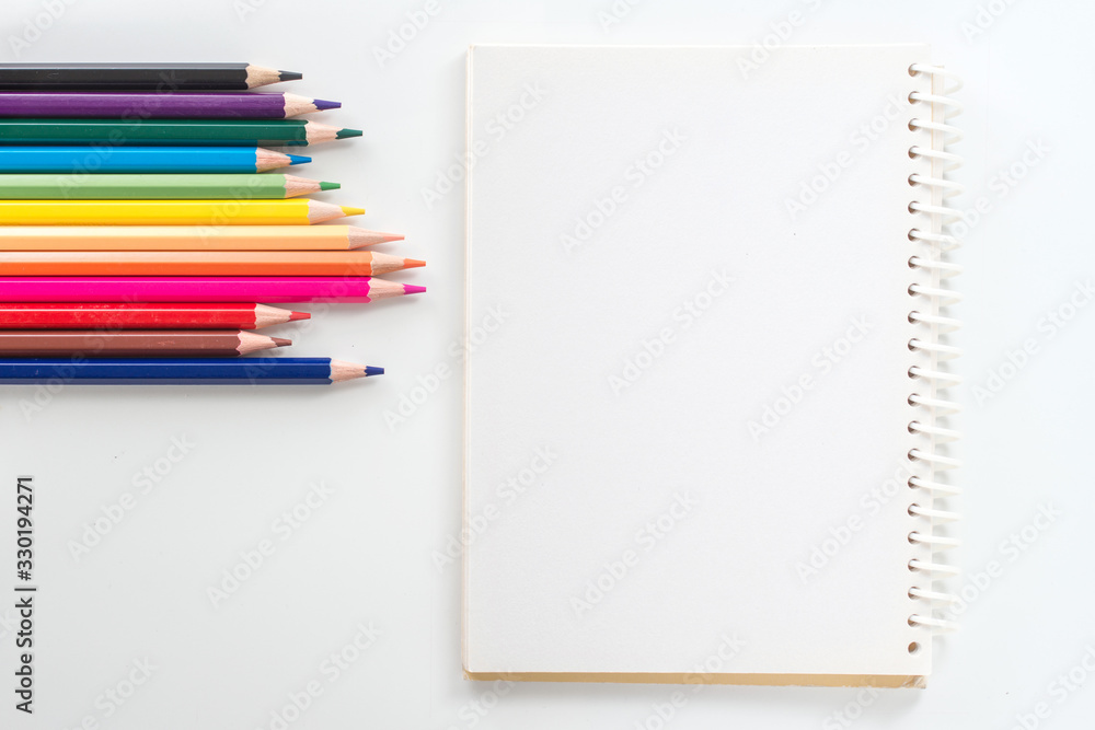 notepad with color pencil on white table view from above notepad with color pencil on white table view from above