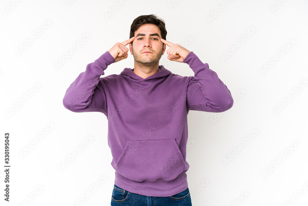 Young man isolated on white background focused on a task, keeping forefingers pointing head.