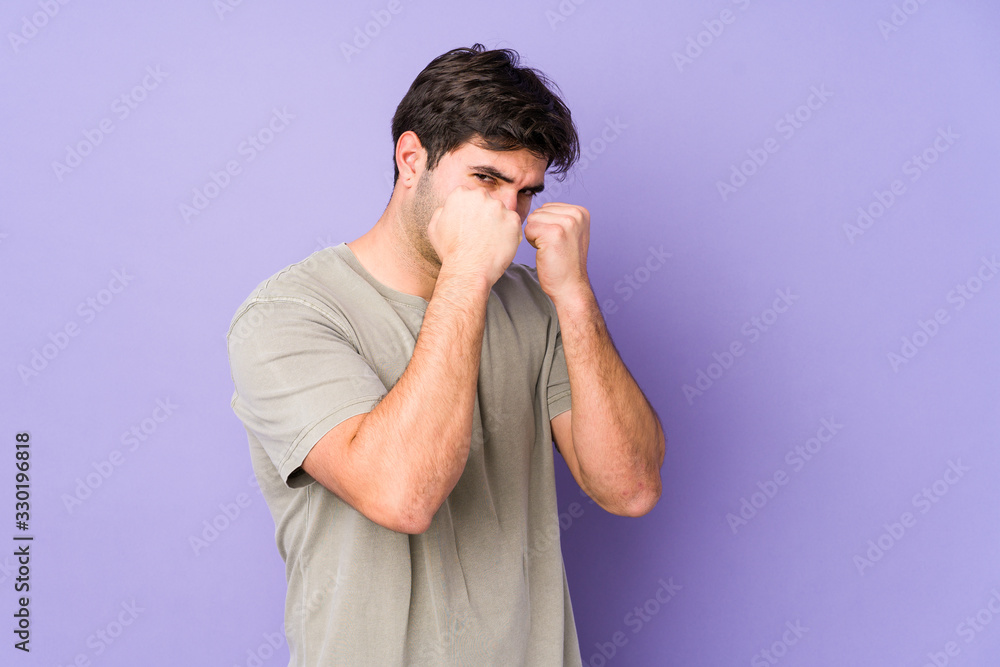 Young man isolated on purple background throwing a punch, anger, fighting due to an argument, boxing. Young man isolated on purple background throwing a punch, anger, fighting due to an argument, boxing.