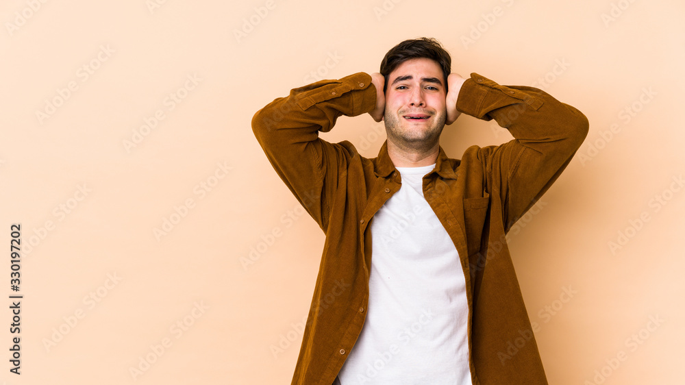 Young man isolated on beige background screaming with rage. Young man isolated on beige background screaming with rage.