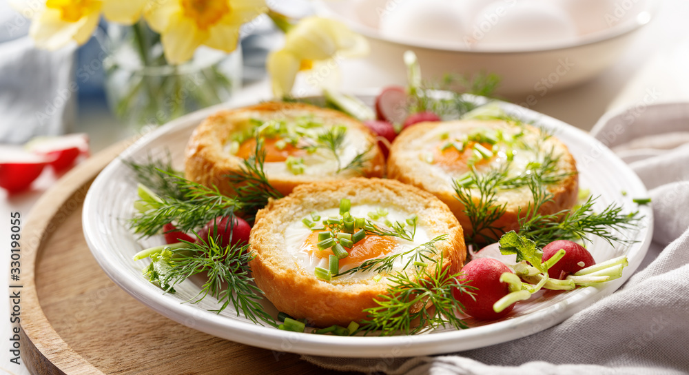 Delicious breakfast baked eggs in bread bowls with the addition of fresh herbs and radishes on a white plate Delicious breakfast baked eggs in bread bowls with the addition of fresh herbs and radishes on a white plate