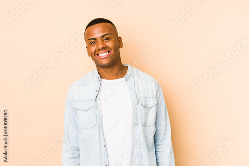 Young latin man isolated on beige background happy, smiling and cheerful.