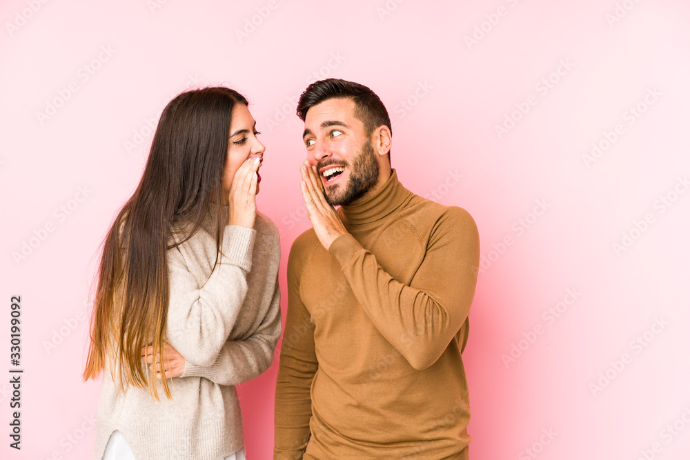 Young caucasian couple isolated is saying a secret hot braking news and looking aside Young caucasian couple isolated is saying a secret hot braking news and looking aside