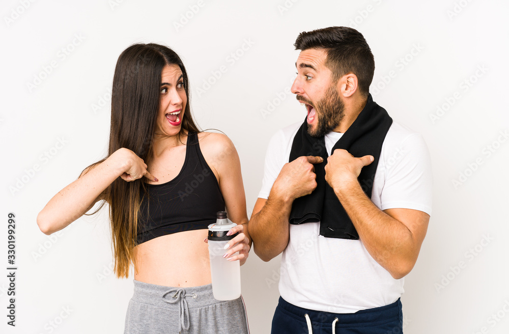 Young caucasian fitness couple isolated surprised pointing with finger, smiling broadly. Young caucasian fitness couple isolated surprised pointing with finger, smiling broadly.