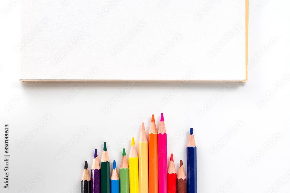 notepad with color pencil on white table view from above notepad with color pencil on white table view from above