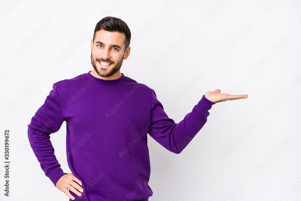 Young caucasian man against a white background isolated showing a copy space on a palm and holding another hand on waist. Young caucasian man against a white background isolated showing a copy space on a palm and holding another hand on waist.