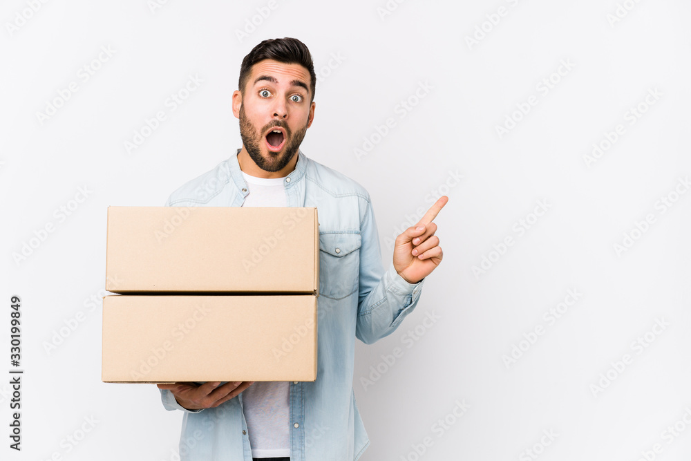 Young caucasian man moving to a new home isolated pointing to the side Young caucasian man moving to a new home isolated pointing to the side