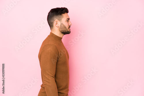 Young caucasian man against a pink background isolated gazing left, sideways pose. photo