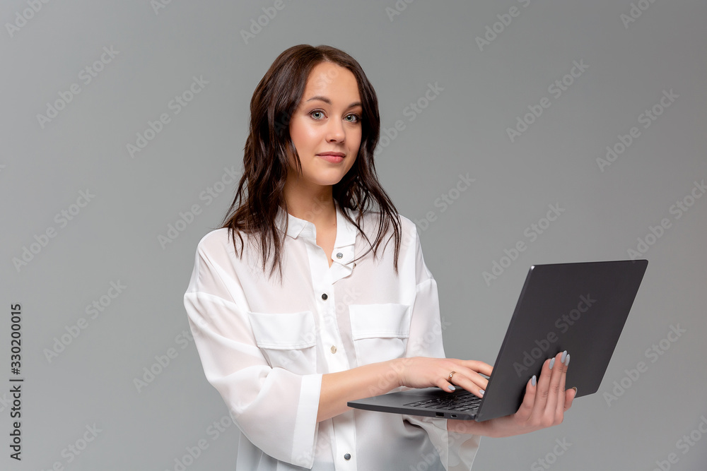 Charming young woman working freelance, remote from office, hold laptop, typing university essay, turn left smiling copy space, stand gray background joyful, browsing web using computer Charming young woman working freelance, remote from office, hold laptop, typing university essay, turn left smiling copy space, stand gray background joyful, browsing web using computer