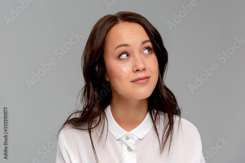 Smiling young business woman in white shirt posing isolated on grey wall background studio portrait. Achievement career wealth business concept. Mock up copy space.