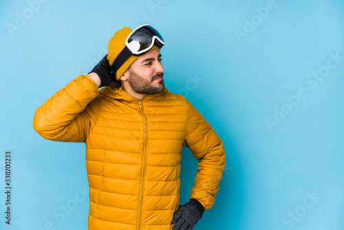 Young skier caucasian man isolated touching back of head, thinking and making a choice. © Asier