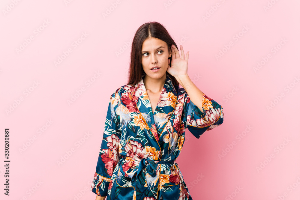 Young caucasian woman wearing a kimono pajama trying to listening a gossip. Young caucasian woman wearing a kimono pajama trying to listening a gossip.