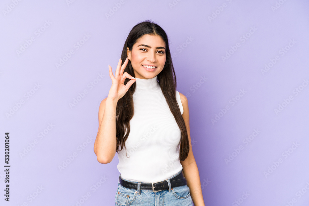 Young indian woman isolated on purple background cheerful and confident showing ok gesture. Young indian woman isolated on purple background cheerful and confident showing ok gesture.