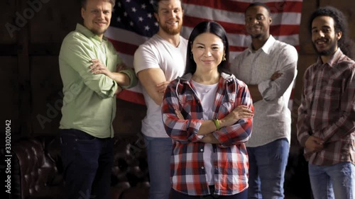 Group of young and mid aged people standing smiling on USA flag on backgroud. Happy immigrants or refugees posing on camera. Young people are happy passing immigration process.